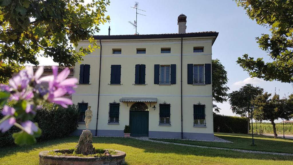 una casa bianca con un fiore viola in primo piano di B&B Le Ripe a Lugo