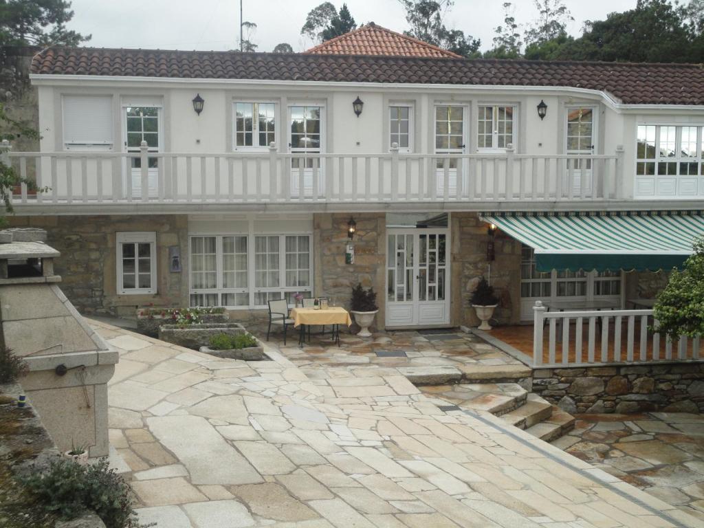 a large white house with a stone patio at Casa Os Batans in Vimianzo