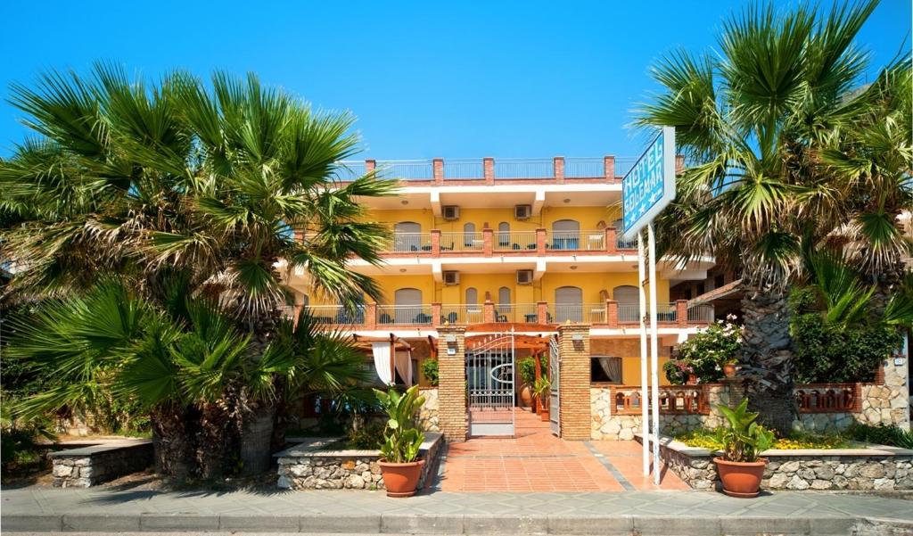 un edificio amarillo con palmeras delante en Hotel Solemar, en SantʼAlessio Siculo