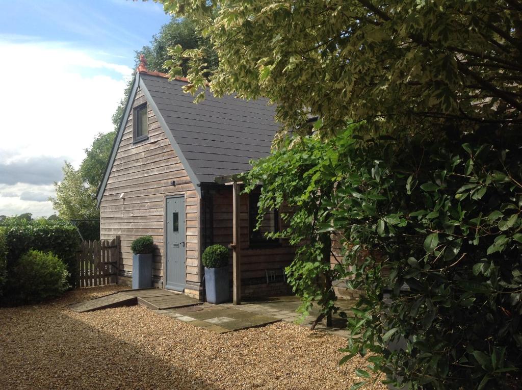 una pequeña casa con una puerta y una valla en The Annex at Meadow Farm, en Cambridge