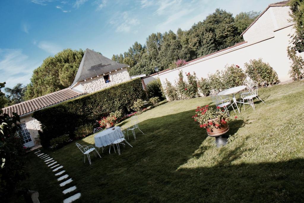 een tuin met stoelen en tafels en een gebouw bij Le Manoir de Marie-Lou in Rauzan