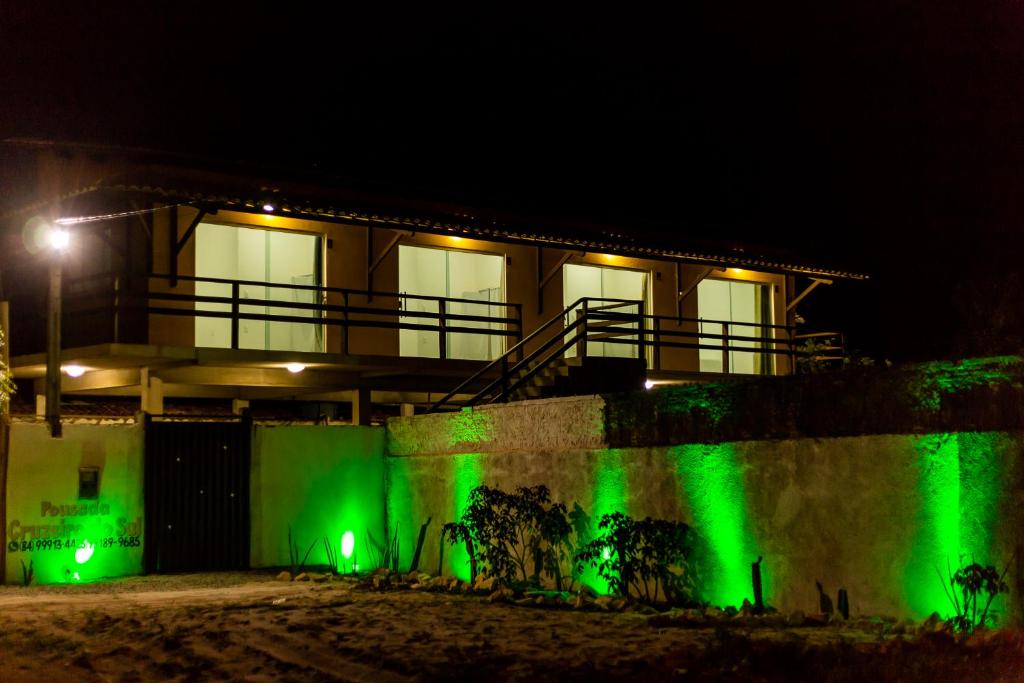 una casa con luces verdes en una pared por la noche en Pousada Cruzeiro do Sul, en São Miguel do Gostoso