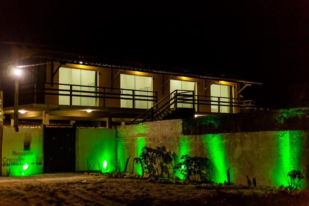 a house with green lights on a wall at night at Pousada Cruzeiro do Sul in São Miguel do Gostoso