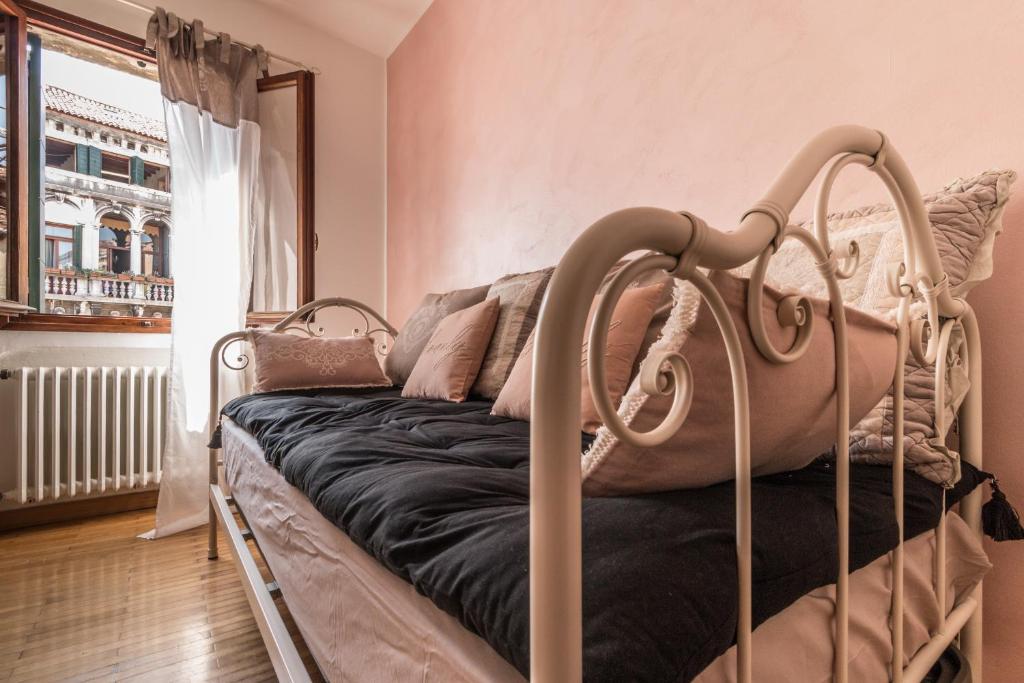 uma cama de metal num quarto com uma janela em CASA DELL'ARTISTA em Veneza