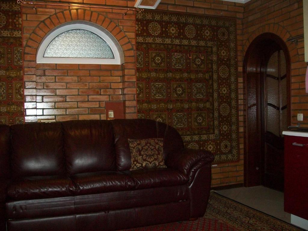 - un canapé en cuir brun dans une chambre avec un mur en briques dans l'établissement atHome, à Soumy