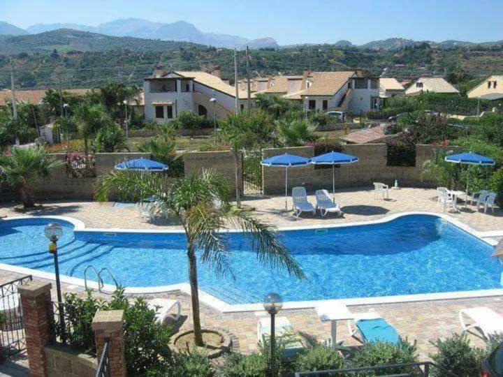 einen Pool mit Stühlen und Sonnenschirmen in einem Resort in der Unterkunft Mansarda Camelie via dei Normanni, 45 in Campofelice di Roccella