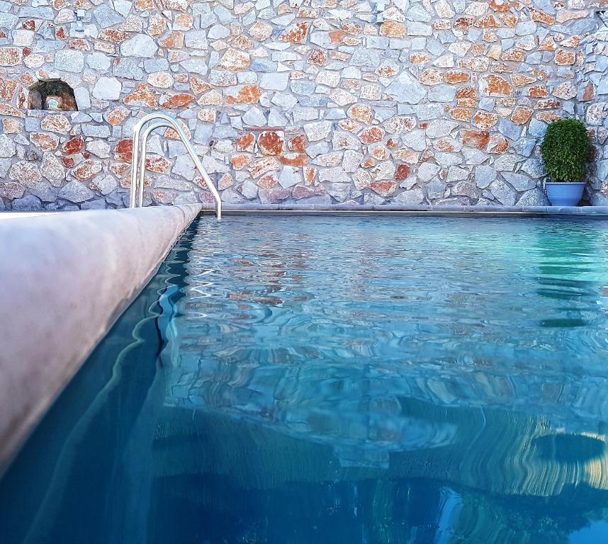 a swimming pool in front of a stone wall at Maistrali in Rodakino