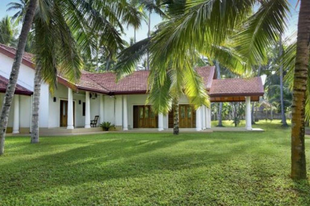 una casa con palme di fronte a un cortile di Coco Villa Peach Tree a Katunayake