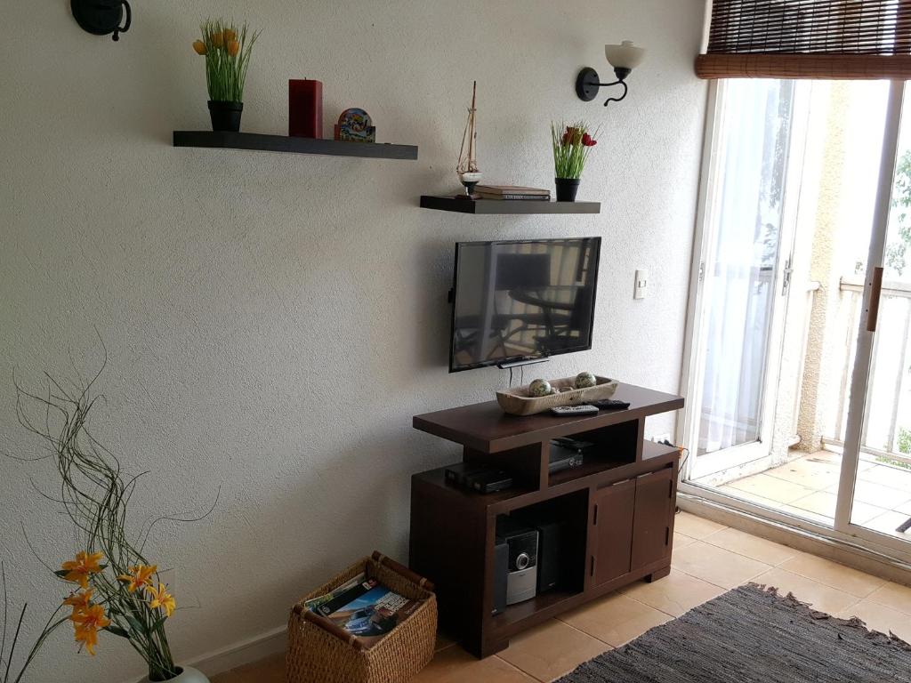 een woonkamer met een flatscreen-tv op een standaard bij Condominio Bahia Pelicanos - Horcon in Horcón