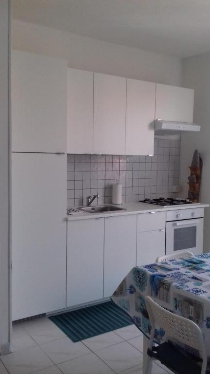 a kitchen with white cabinets and a sink and a table at casa letizia in Porto Recanati