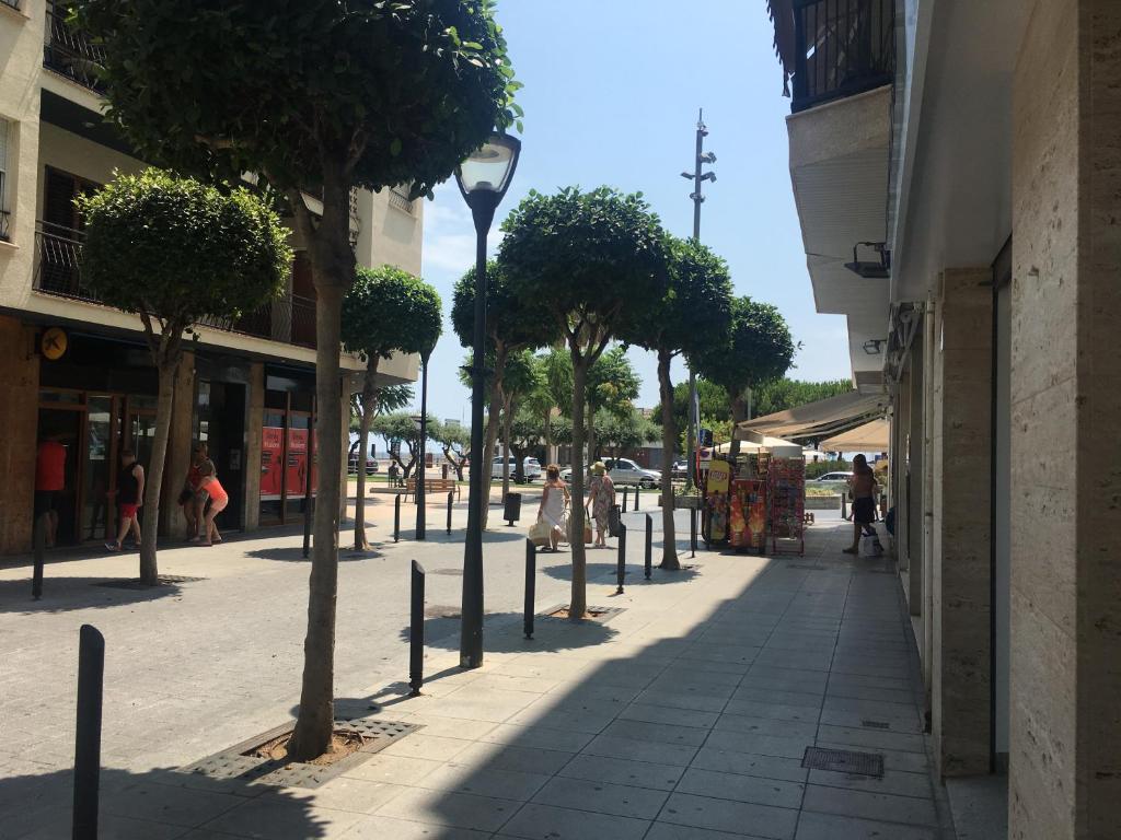 a street with trees and people walking down a sidewalk at Club Nautic in Cambrils