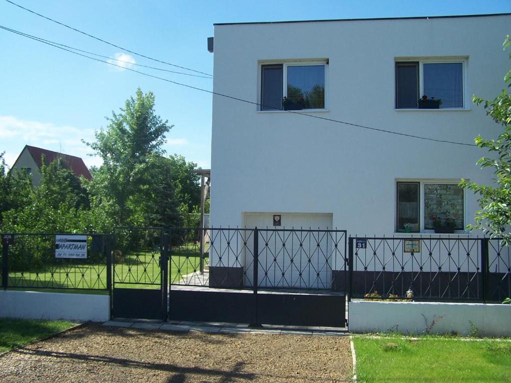 a white building with a black gate in front of it at Aliz Apartman in Nyíregyháza