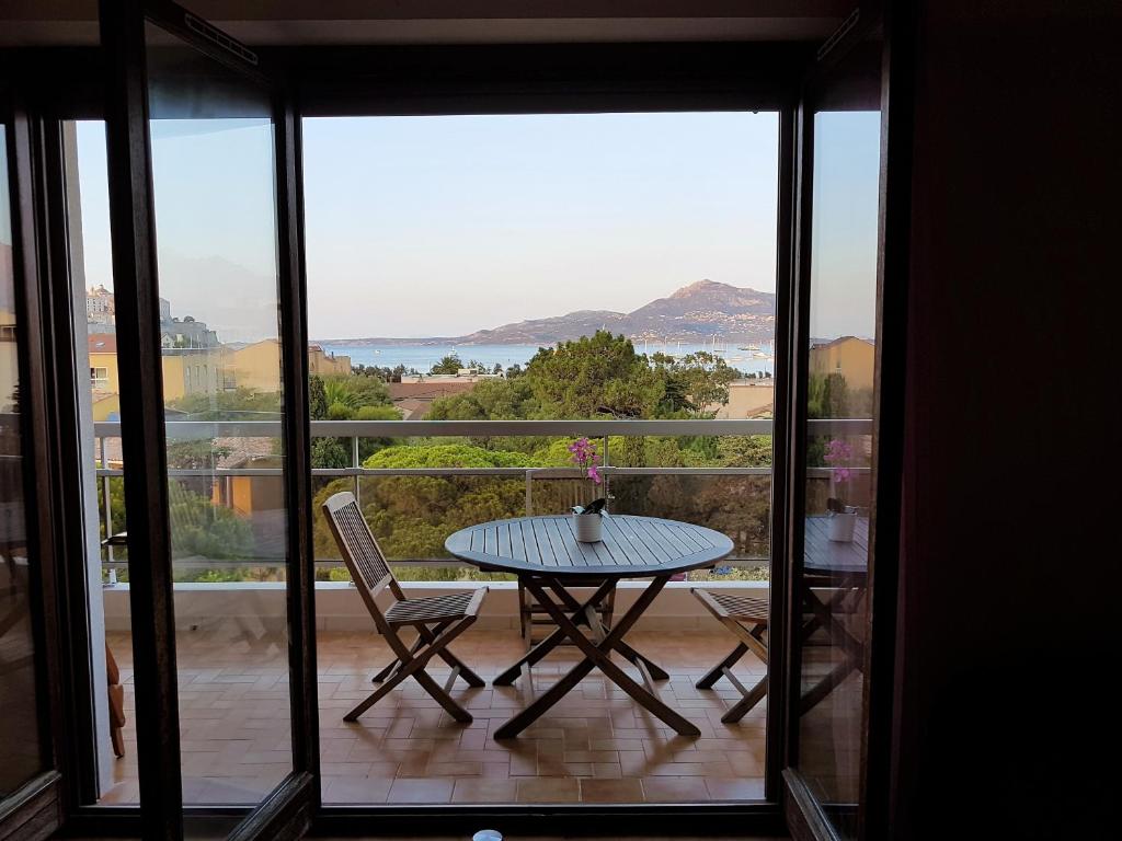 una mesa y sillas en un balcón con vistas al océano en Casa Orsoni en Calvi