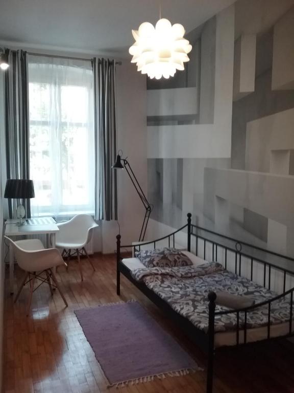 a bedroom with a bed and a desk and a chandelier at POKOJE MŁODZIEŻOWE in Toruń