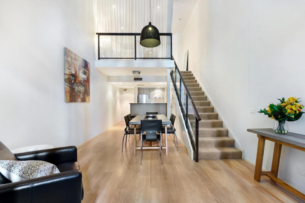 ein Wohnzimmer mit einer Treppe und einem Tisch und Stühlen in der Unterkunft Surry Hills Modern One Bedroom Apartment -GOUL in Sydney