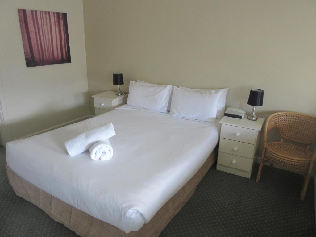 
a hotel room with a bed, chair, and nightstand at Abel Tasman Airport Motor Inn in Launceston
