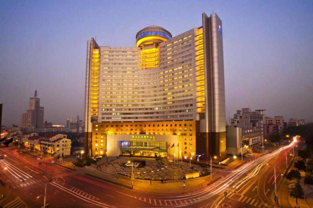 un grand bâtiment avec des lumières jaunes sur une rue de la ville dans l'établissement Huafang Jinling International Hotel Zhangjiagang, à Zhangjiagang