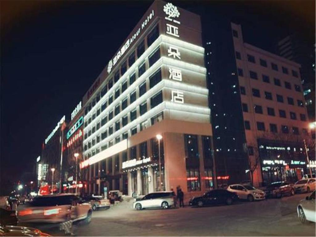 un gran edificio con coches estacionados en un estacionamiento en Atour Hotel Shuangyong Ave, en Yan'an