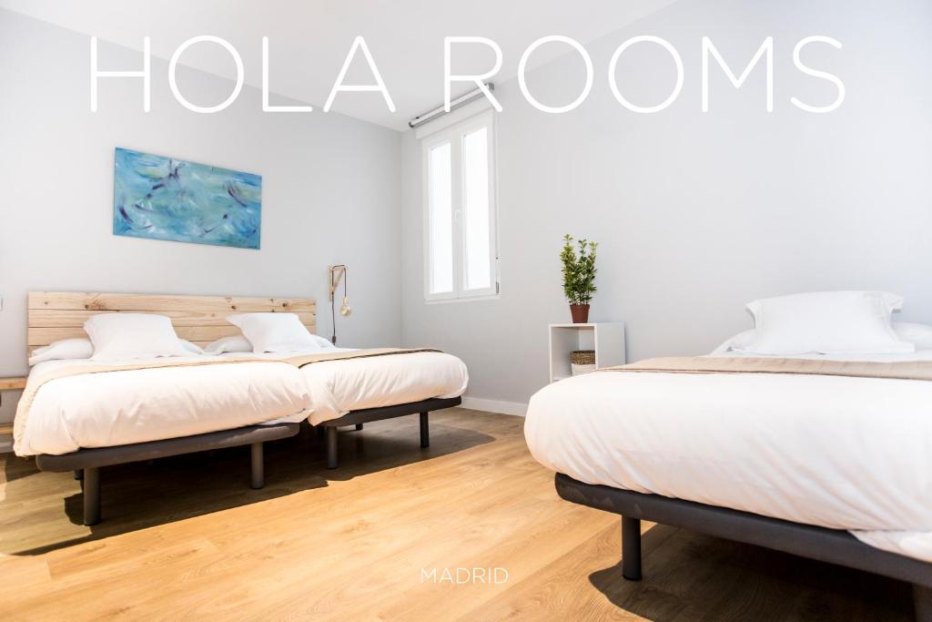 twee bedden in een kamer met witte muren bij Hola Rooms in Madrid