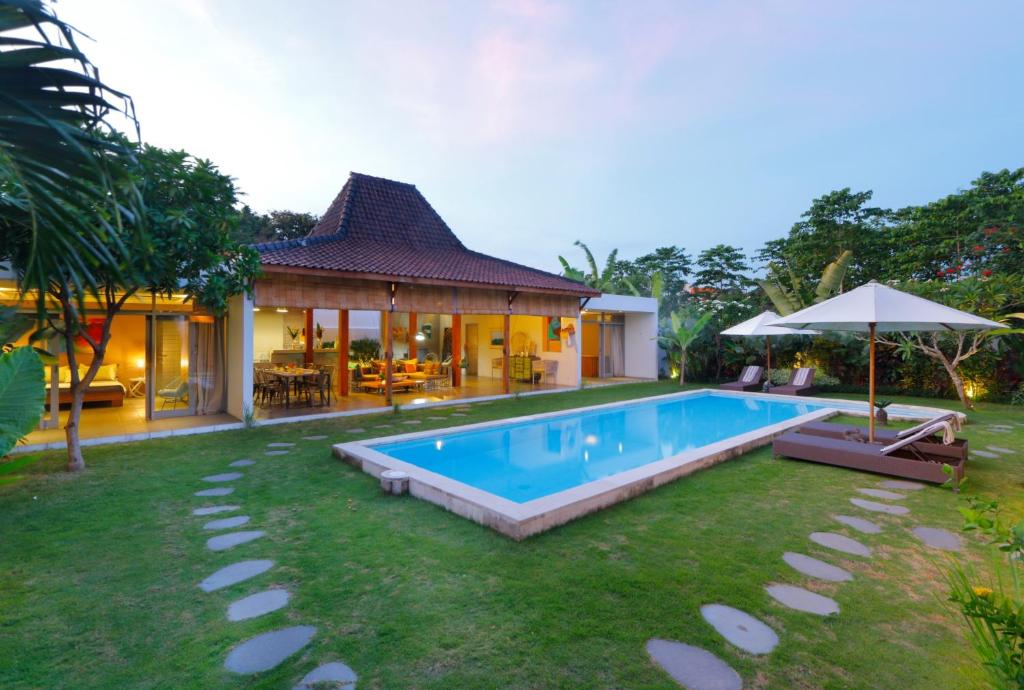 a backyard with a swimming pool and a house at Villa Mitsouko by Optimum Bali Villas in Seminyak