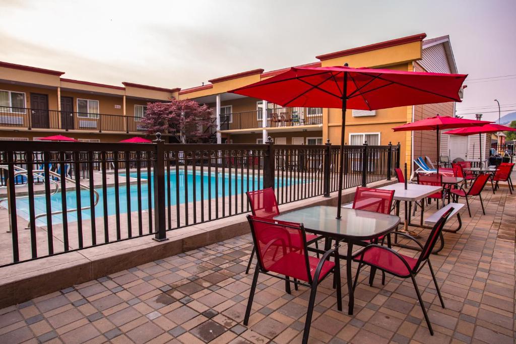 a patio with tables and red chairs and a pool at Sahara Courtyard Inn Penticton in Penticton