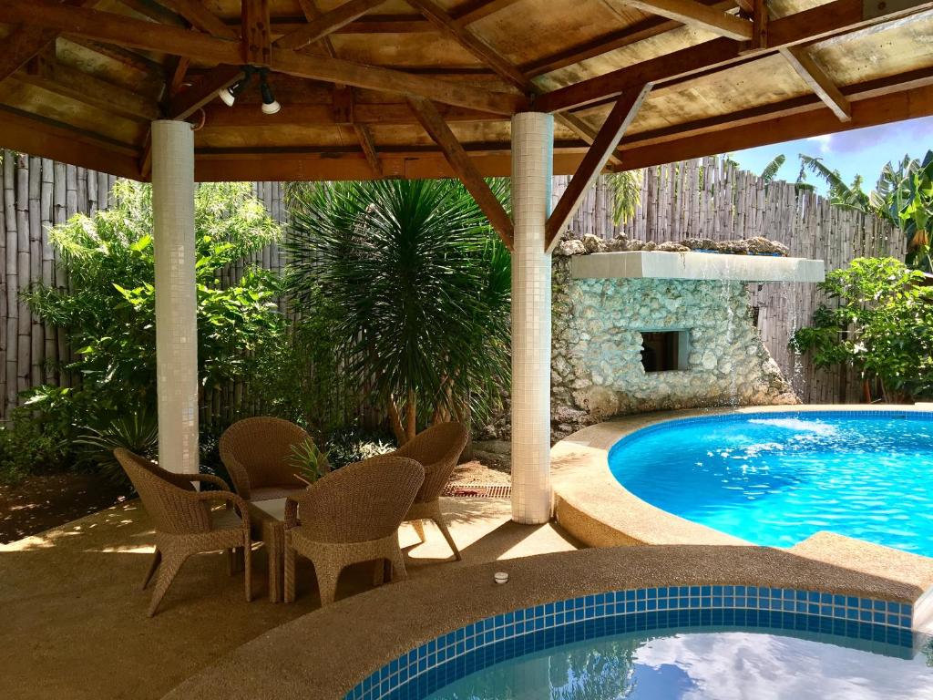 un patio con piscina, sillas, mesa y piscina en Lapu-Lapu Cottages & Restaurant en Isla de Mactán