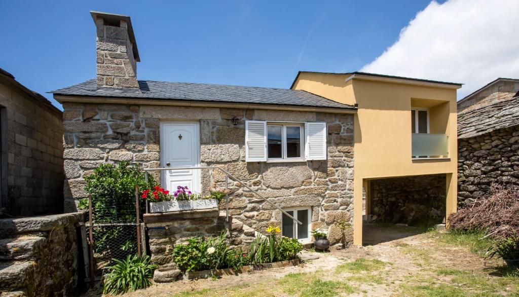 ein altes Steinhaus mit einer weißen Tür und Fenstern in der Unterkunft Casa Amarela in Arouca