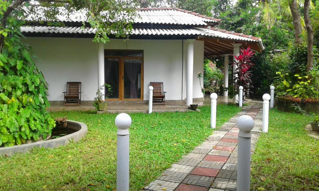 a small house with a pathway in front of a yard at River Retreat Sigiriya in Sigiriya