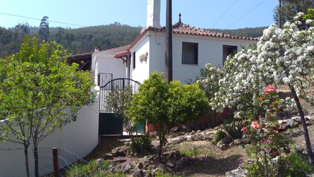ein weißes Haus mit blühenden Bäumen davor in der Unterkunft Casa da Milharica in Figueiró dos Vinhos