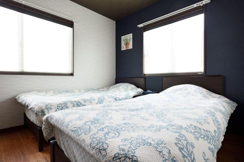 2 Betten in einem Schlafzimmer mit 2 Fenstern in der Unterkunft Miyabi in Kyoto