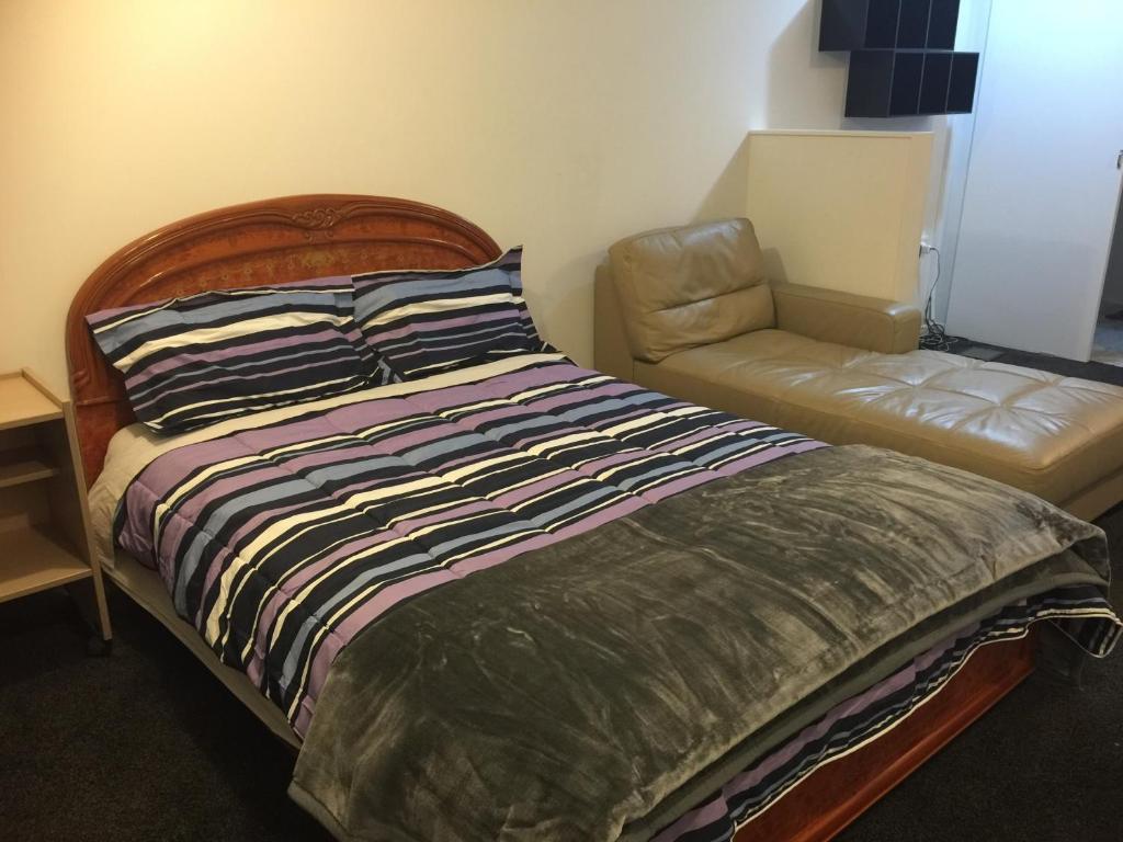 a bed and a chair in a room at K&R Orewa homestay in Orewa