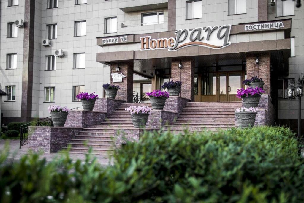 a home page building with potted plants on the stairs at Hotel Home Parq in Ekibastuz