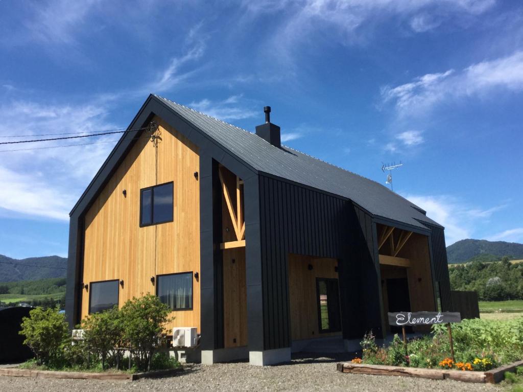 a black and wooden barn with a black roof at Element in Nakafurano