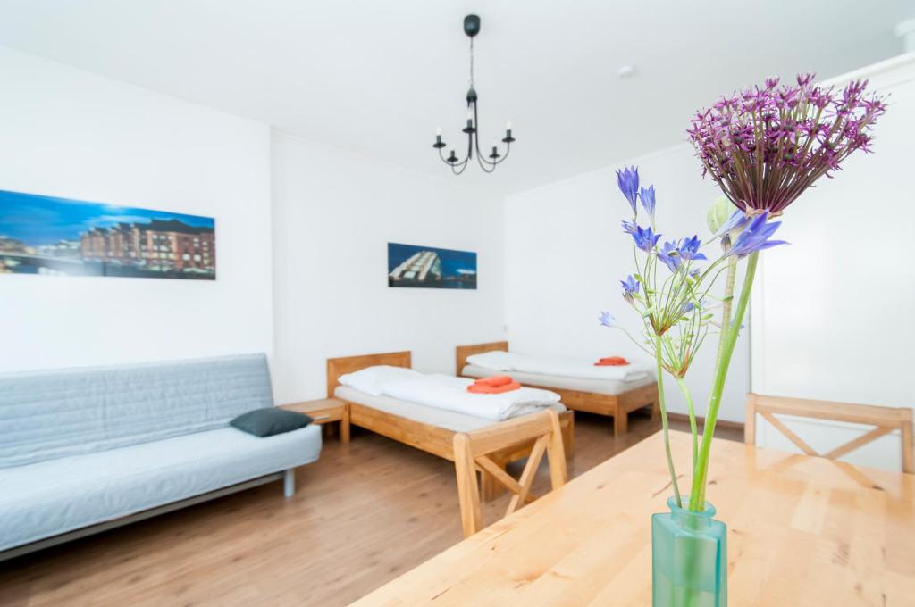 a living room with two beds and a vase with purple flowers at City-Appartements Nordkanalstraße - Monteurunterkunft in Hamburg