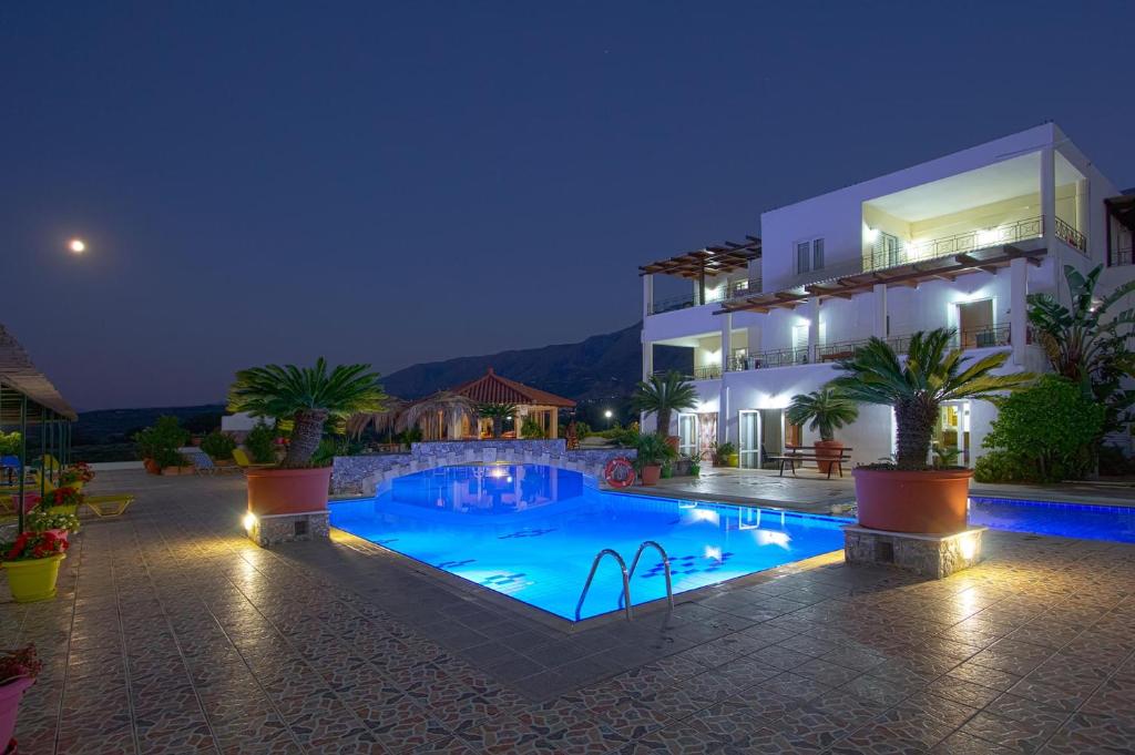 a villa with a swimming pool at night at Pinelopi Apartments in Georgioupolis