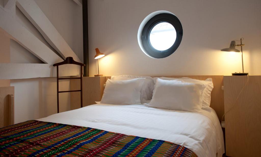 a bedroom with a white bed with a round window at Coimbra Vintage Lofts Apartments in Coimbra