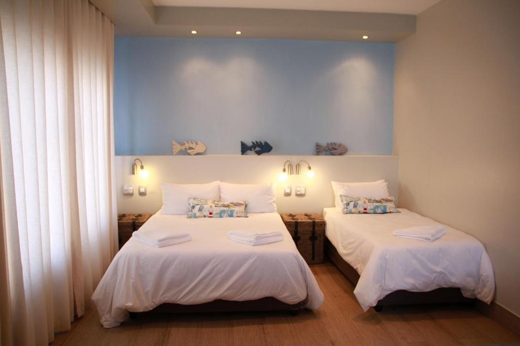 a bedroom with two beds with white sheets at Sea Wind Self Catering Cottages in Swakopmund