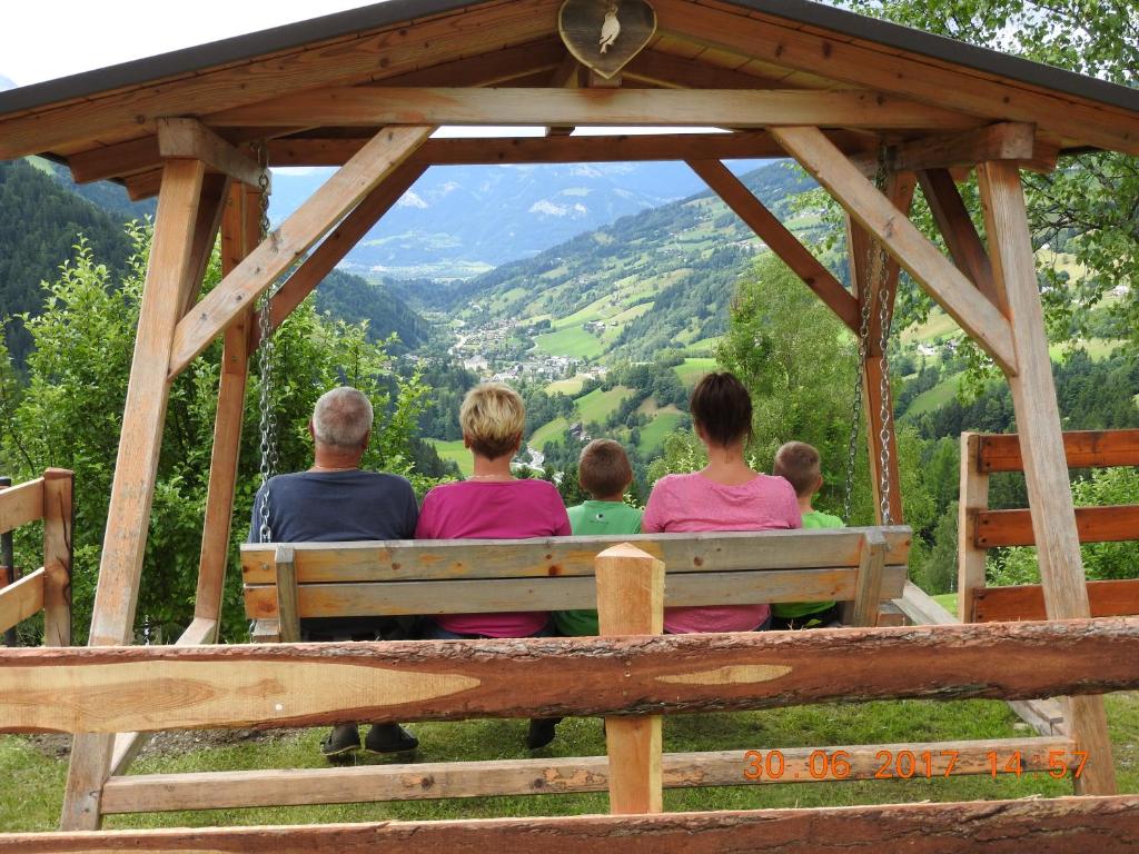 a family sitting on a bench in a gazebo at Ertlschweigerhaus Pension - Appartements - Zimmer in Donnersbach