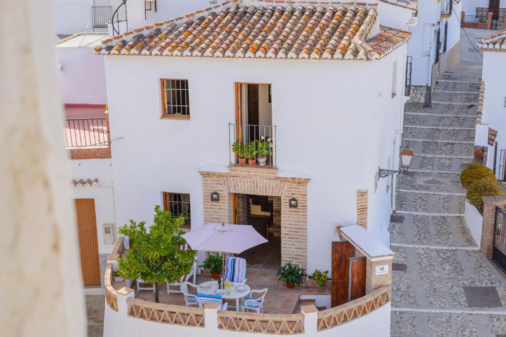 vistas a un edificio blanco con mesa y sombrilla en "El Porton" (El Borge ,Malaga)., en Borge