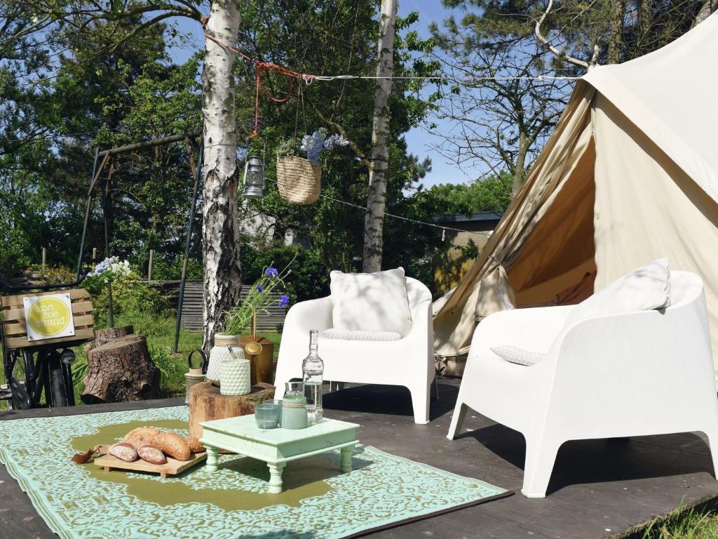 un patio con 2 sillas, una mesa y una tienda de campaña en Charming Tent Lodge in Callantsoog near Beach, en Callantsoog