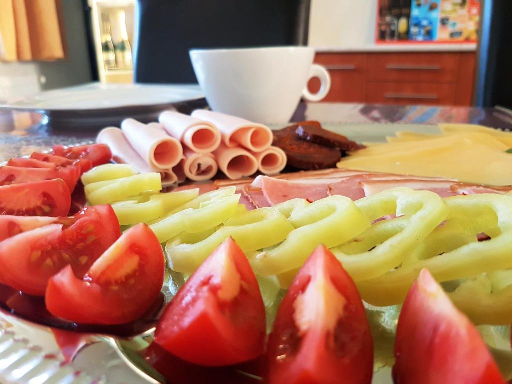 a plate of food with tomatoes and cheese on a table at Akácliget Vendégház és Major in Ófehértó