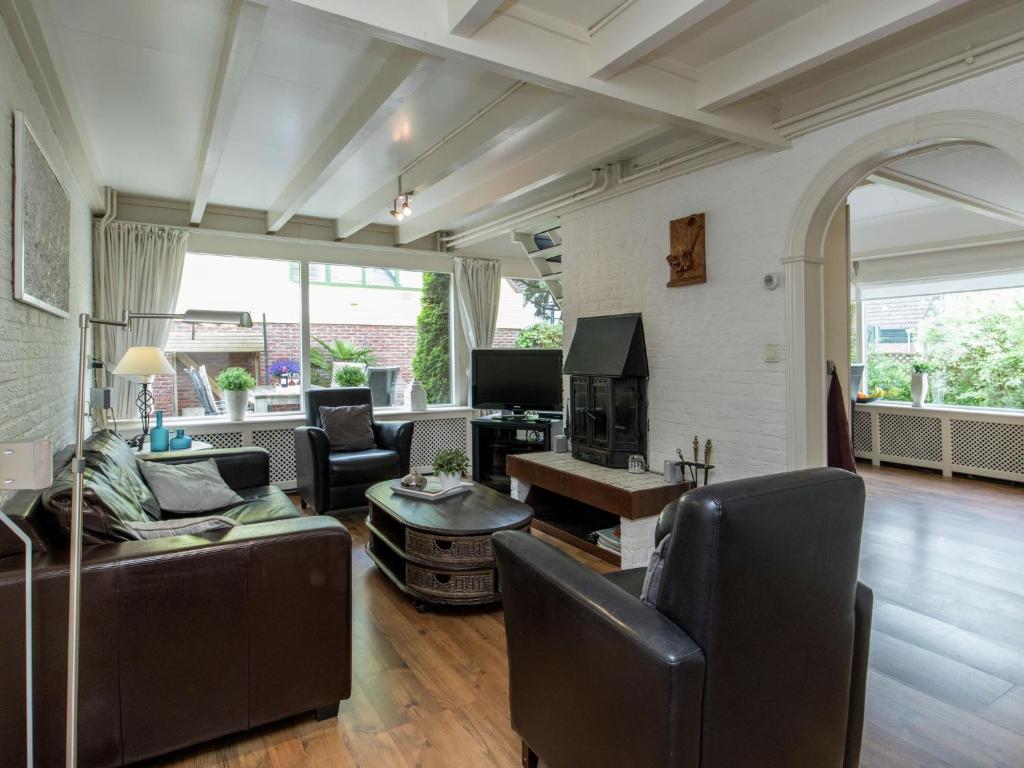 uma sala de estar com um sofá e cadeiras e uma televisão em Cosy Holiday Home in Noordwijkerhout near Lake em Noordwijkerhout
