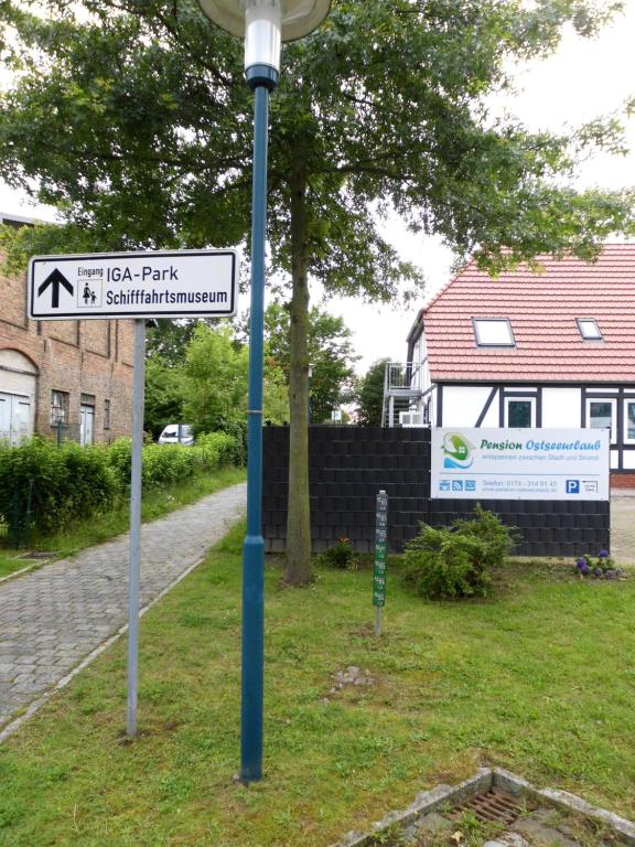 eine blaue Stange mit einem Straßenschild im Gras in der Unterkunft Pension Ostseeurlaub in Rostock