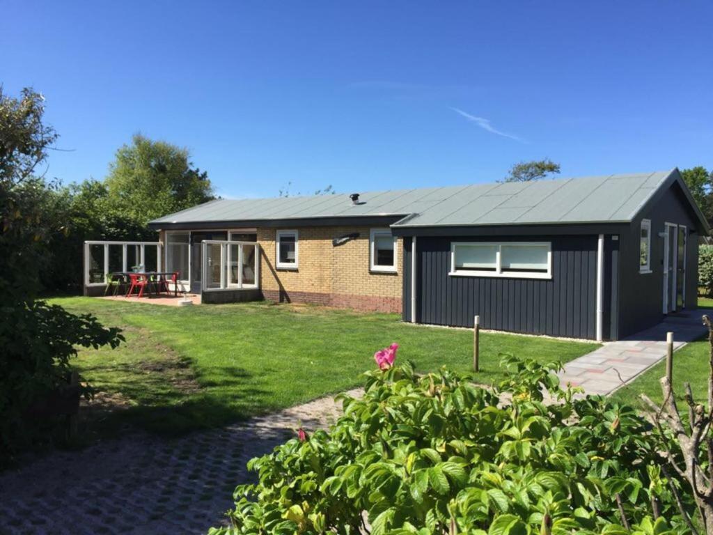 a small house with a black roof at bungalow situated directly at a large sand dunes in Ballum