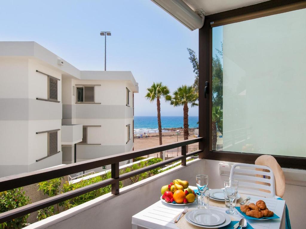 サンアグスティンにあるBeachfront Apartment Siesta 21 San Agustin Playa by VillaGranCanariaのビーチを望むバルコニー(フルーツ付きテーブル付)