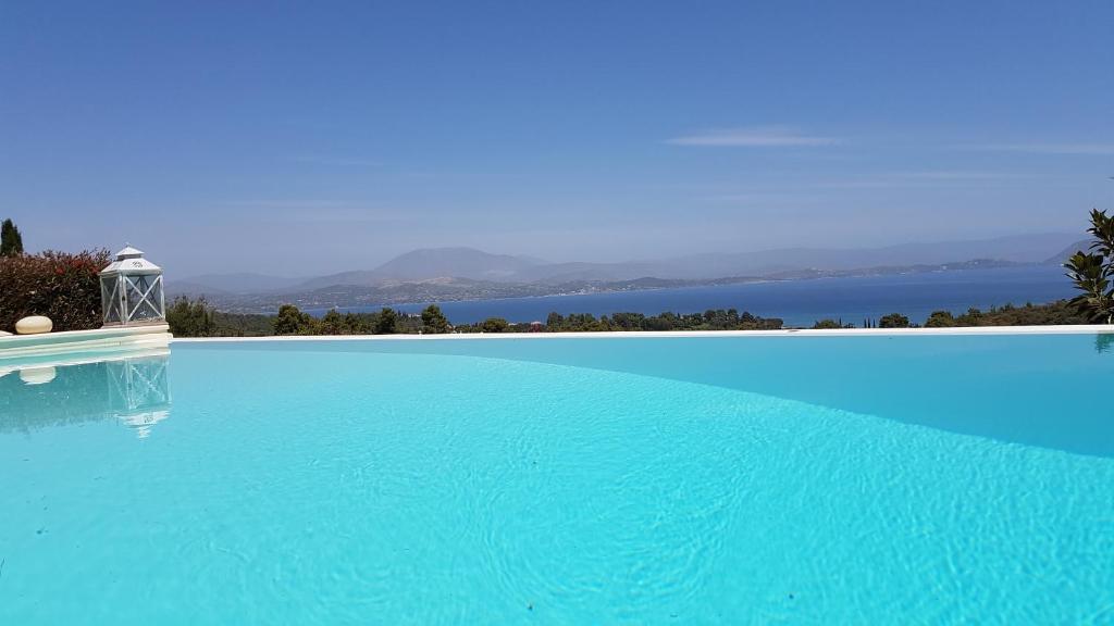 a large blue swimming pool with a view of the water at Big Blue Villa Porto Heli in Porto Heli