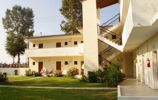 a large white house with a staircase in the yard at Palatino Studios in Agia Paraskevi