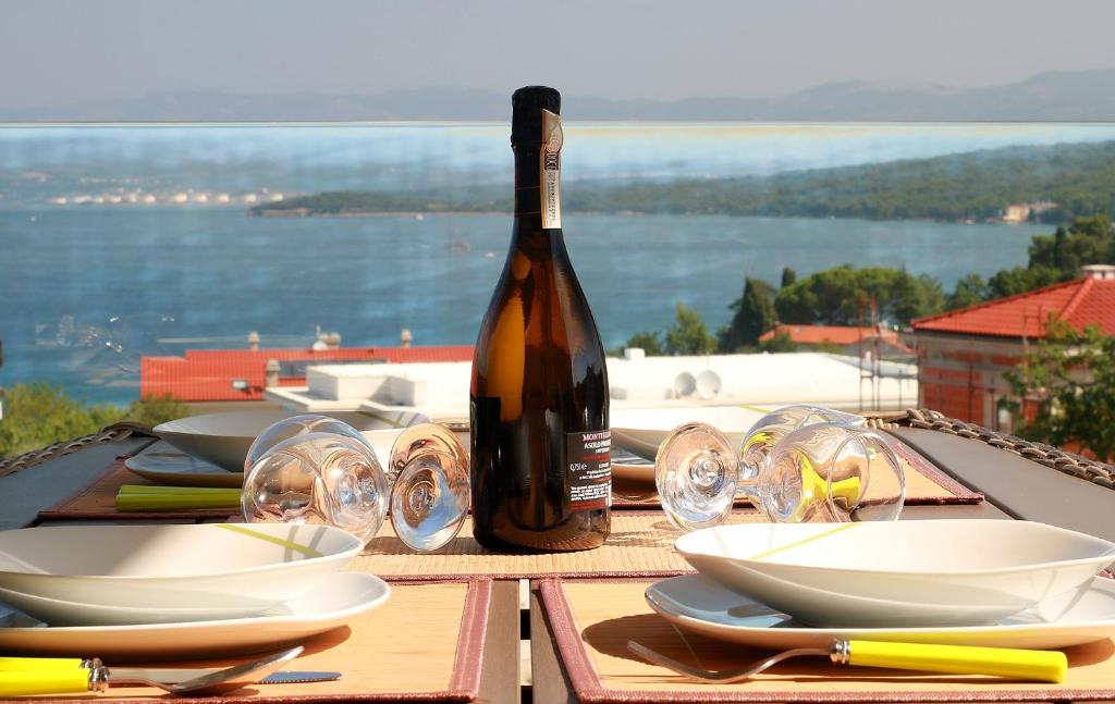 a bottle of wine sitting on a table with glasses at Apartment Porpo in Malinska