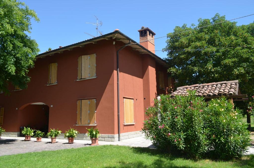 una casa roja con plantas delante de ella en La Maison B&B di Brigitte e Simone, en Bentivoglio