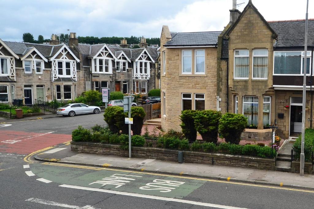 a street with houses and a parking lot with a car at Drumorne in Edinburgh